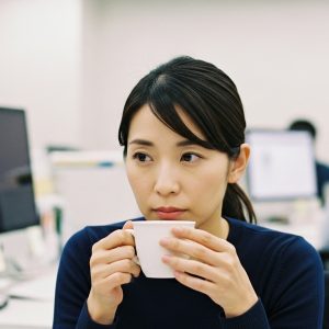 考え込んでいるような表情でコーヒーカップを見つめている女性