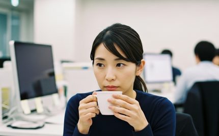 考え込んでいるような表情でコーヒーカップを見つめている女性